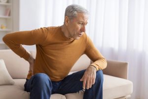 unhappy man holding back in pain